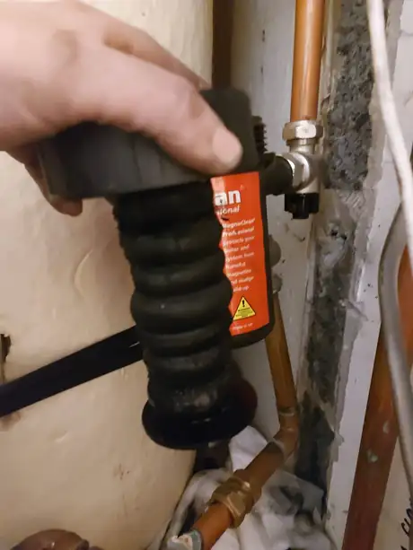 A magnetic system filter being opened for cleaning on copper pipework