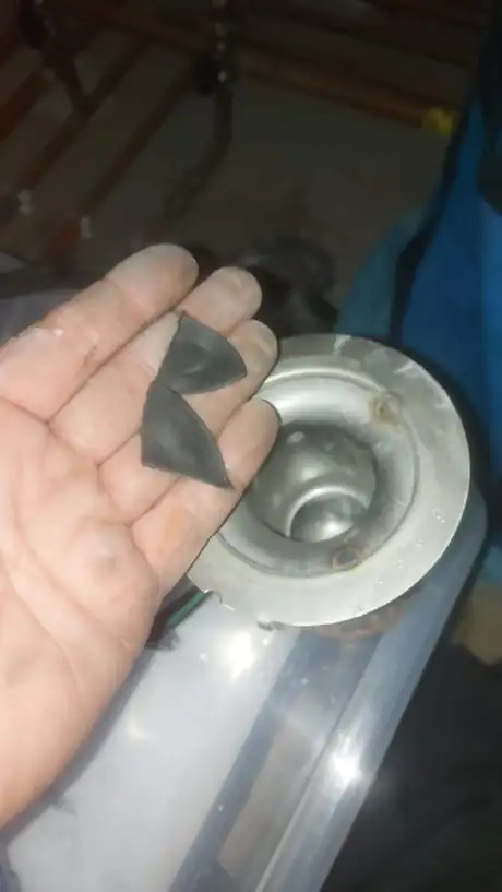 A worn immersion component held in the hand beside a hot water cylinder