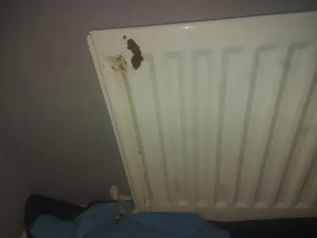 A radiator lifted off the wall and stood on a dust sheet, stained along the top