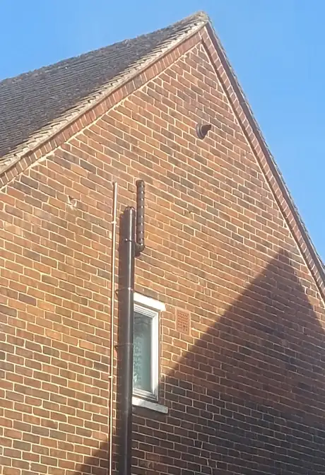 A flue running up the outside gable wall of a brick house