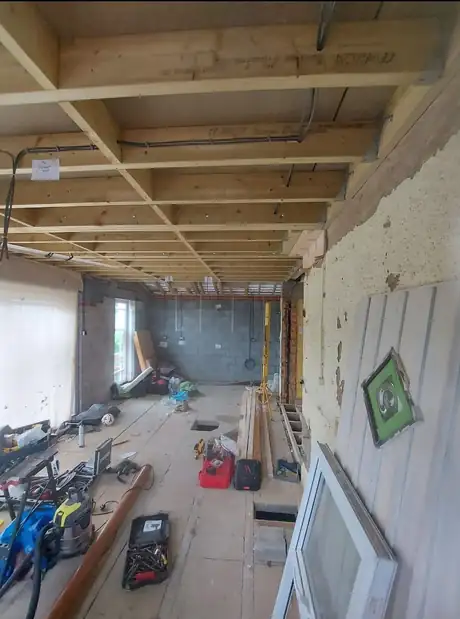 A room stripped back to joists with tools laid out during a heating install