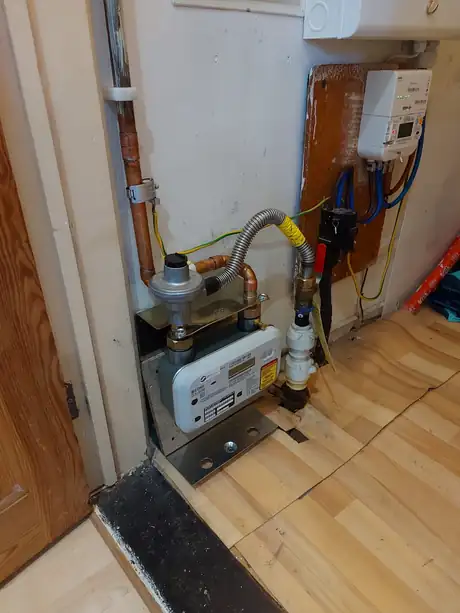 A gas meter and its pipework beside a doorway