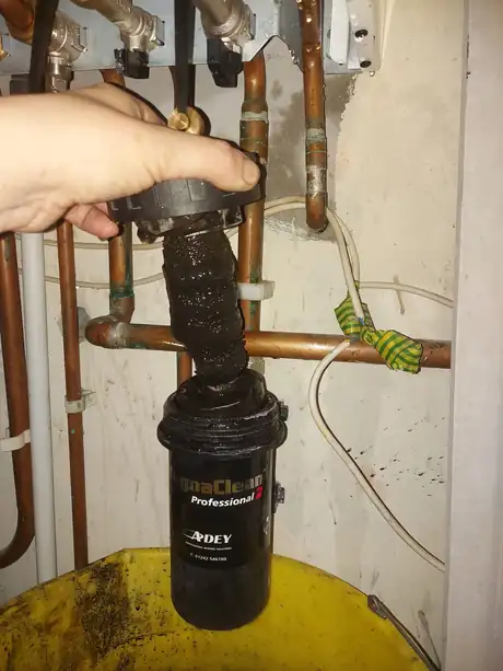 A MagnaClean Professional filter fitted beside a hot water cylinder