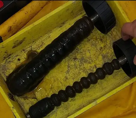 A filter magnet lifted out coated in black sludge