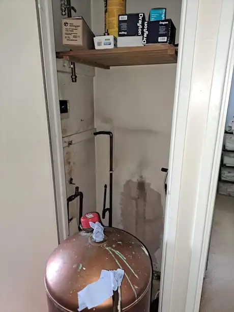 A copper expansion vessel fitted in a cupboard