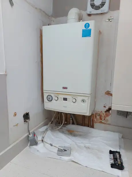 A boiler on the wall with dust sheets down during the install