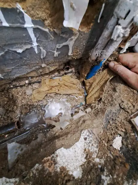 A rotted floor joist beside heating pipework