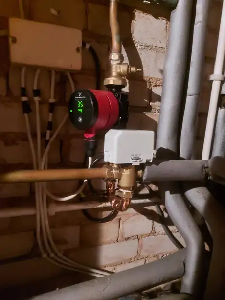 A circulating pump and motorised valve on a brick wall