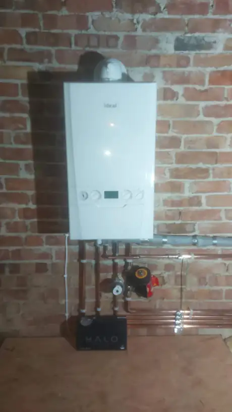 An Ideal boiler fitted on exposed brick with a system filter beneath