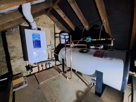 A boiler, cylinder and expansion vessel installed together in a loft