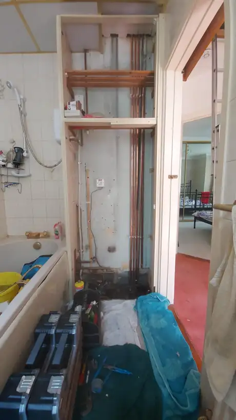 A bathroom stripped back with radiators stacked ready to refit
