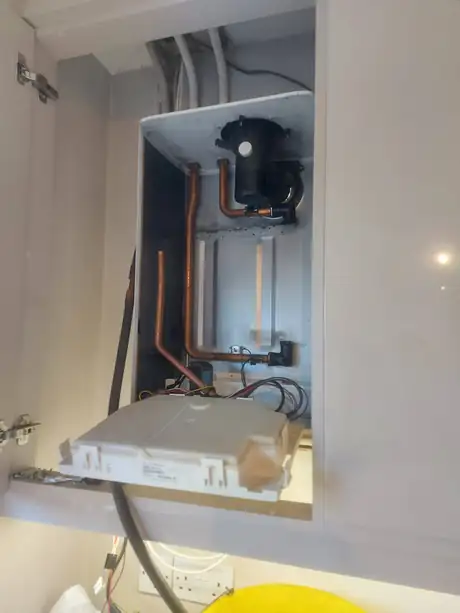 A boiler in a cupboard with its lower panel dropped
