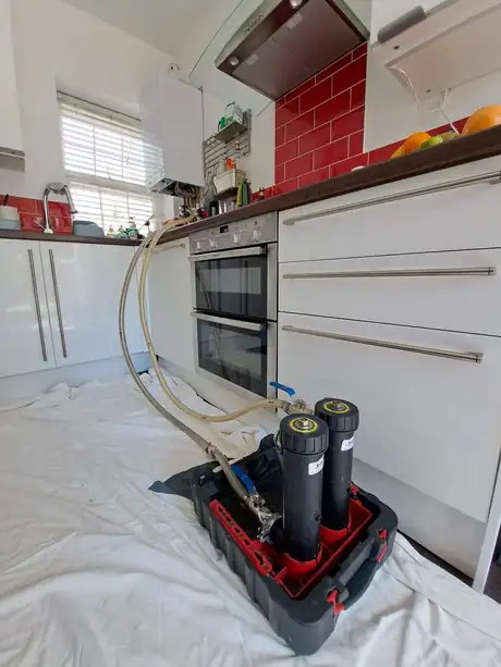 A power flush unit set up in a kitchen on dust sheets