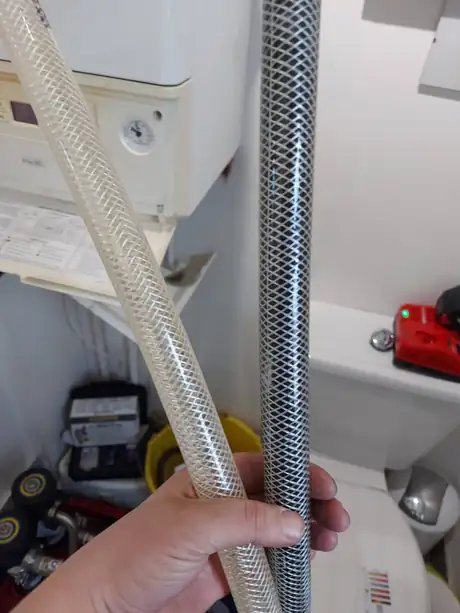 A new flexible hose held beside the furred old one it replaced
