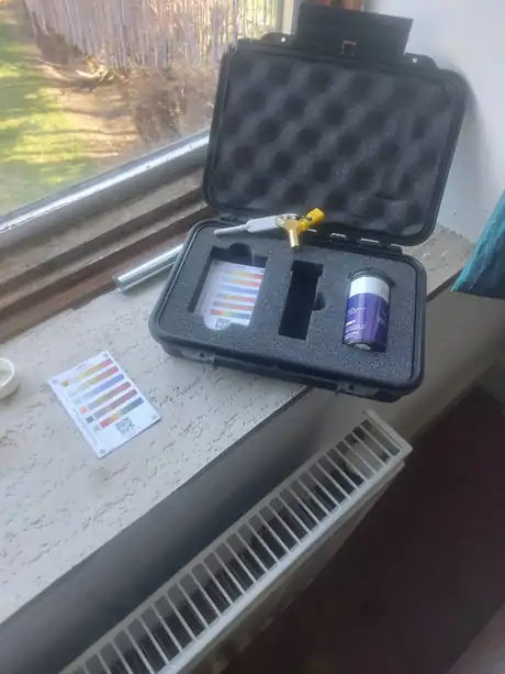 A water testing kit open on the windowsill beside a radiator