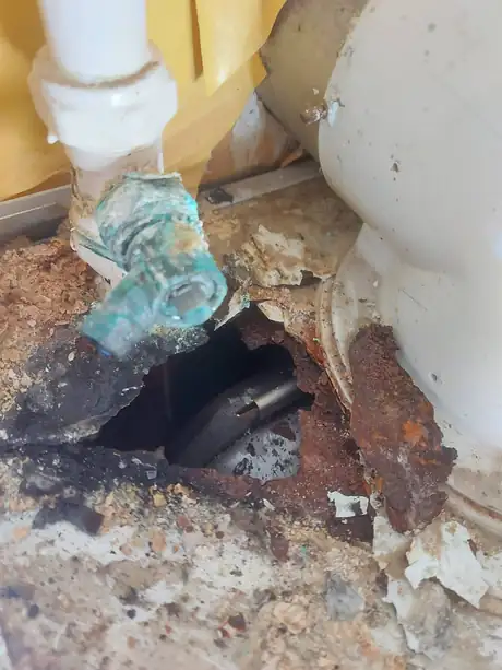 A rotted floor around heating pipework
