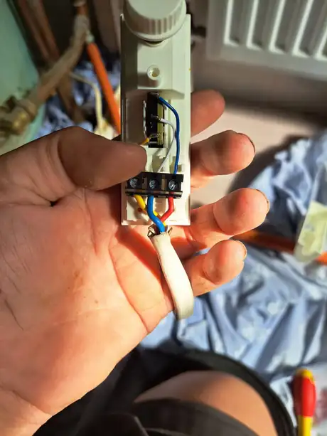 A wiring connection block held open in the hand