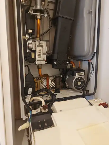 An opened boiler showing the pump, gas valve and internal pipework