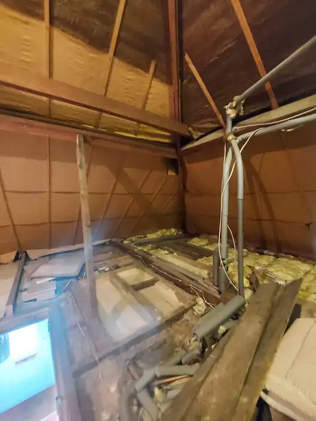 A loft with the floor opened and pipework run through