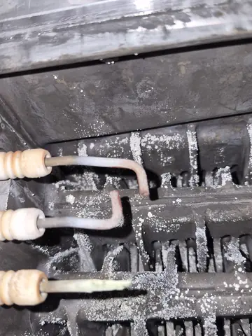 A heat exchanger caked in soot and scale, lifted out of a boiler during a strip clean