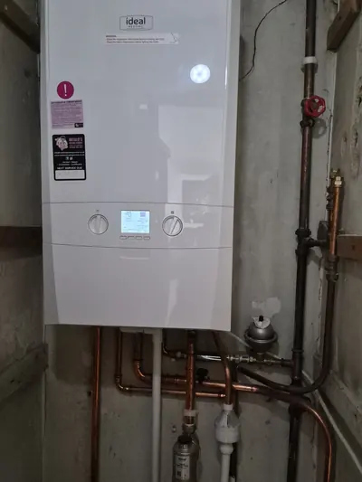 An Ideal boiler fitted with the gas, water and condense pipework run tight to the wall below it
