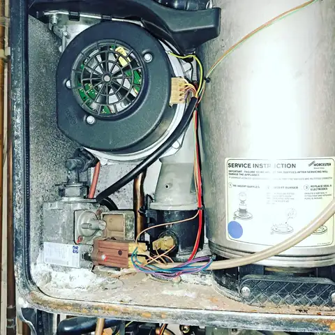 The inside of an open boiler, its components and casing covered in dirt, scale and corrosion