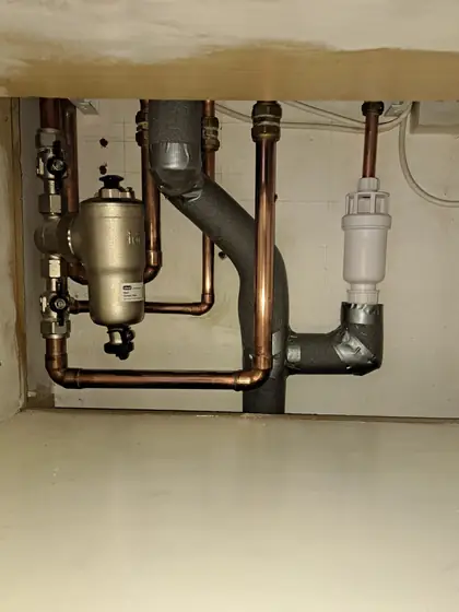 A magnetic system filter and an automatic air vent fitted on lagged pipework beneath a boiler